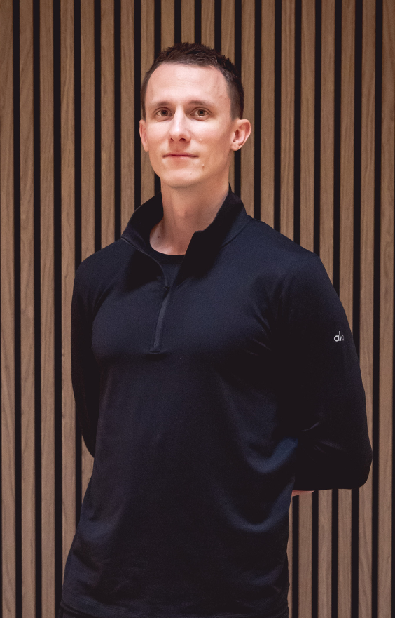 Portrait d'un homme blanc en tenue noire, Jérémy, passionné par la santé par le sport et enseignant le Pilates avec le Reformer pour favoriser l'équilibre physique et mental